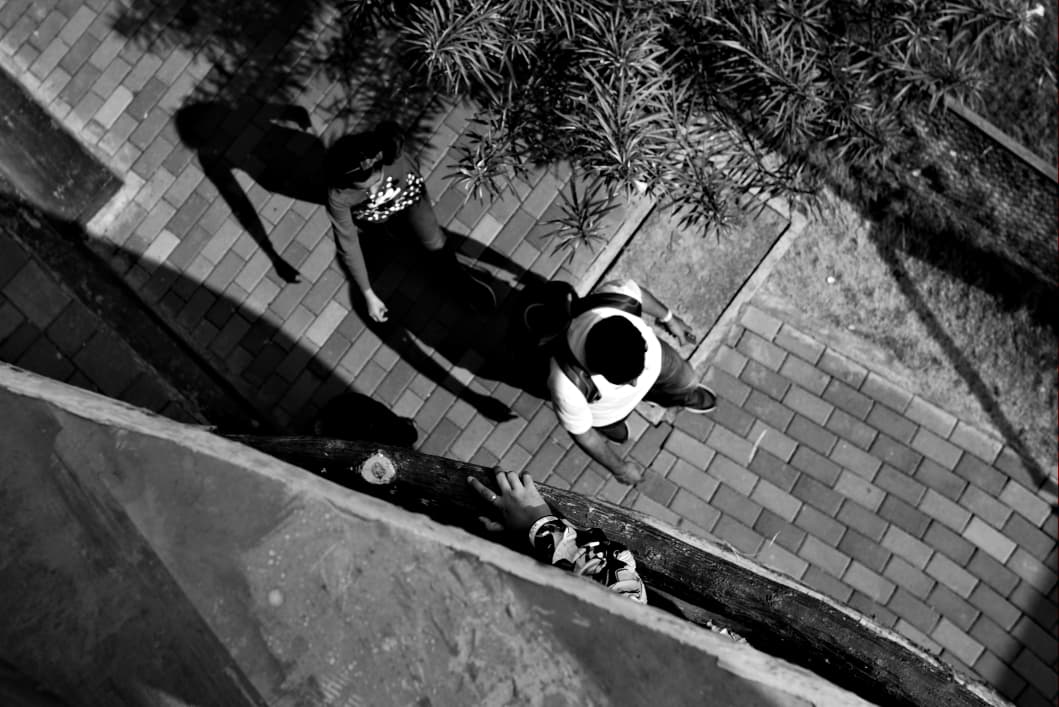 Two people walking on paving seen from directly above, their shadows stretched beside them