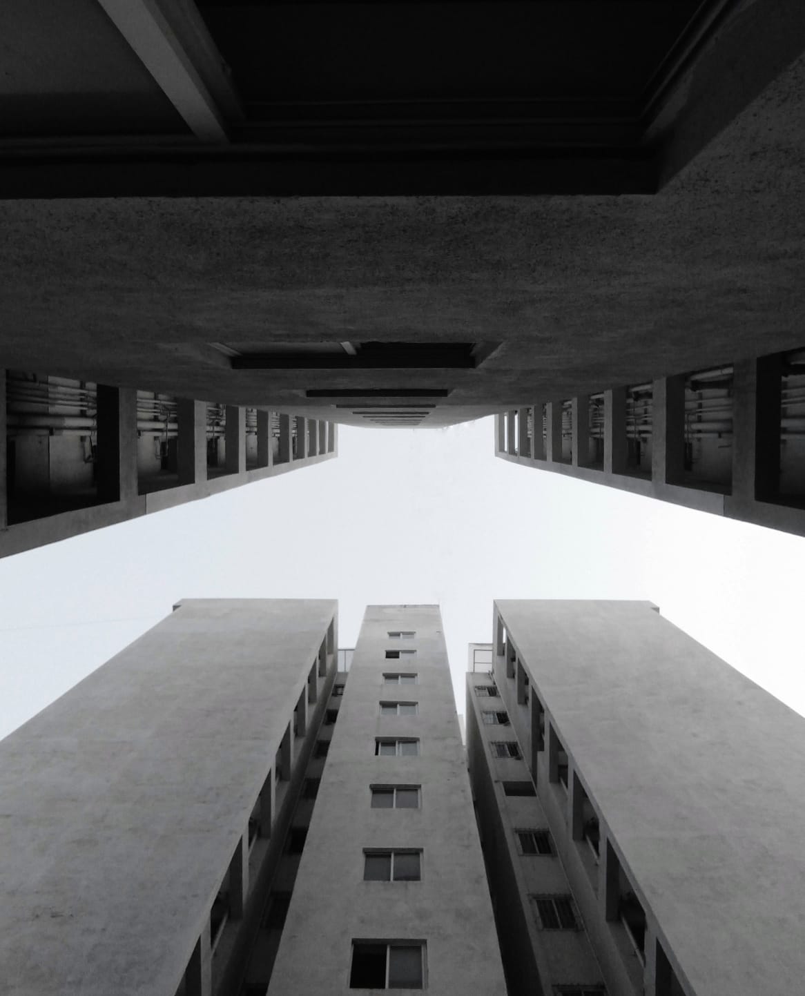 Looking straight up between two apartment towers, sky cut into a narrow strip