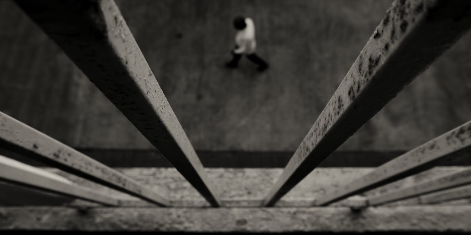 Looking down between concrete railings at a small figure walking below